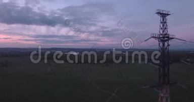 俯视图，空中：高压塔在田野和小镇的地平<strong>线上</strong>，云彩在夕阳的光芒。 4K